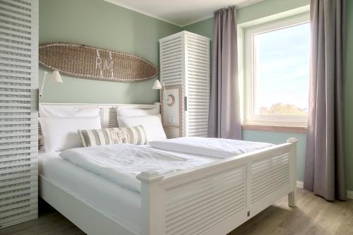 a white bed in a room with a window at Beach Apartments Büsum in Büsum