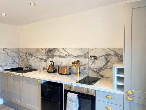 a kitchen with a marble counter top and blue cabinets at Kaoglen - Alpine Pod - Hot Tub - Cairngorms - Pitlochry in Kirkmichael