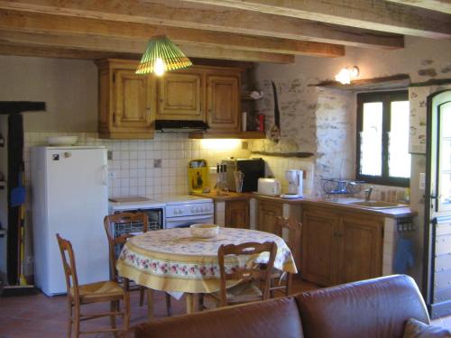une cuisine avec une table et des chaises et un réfrigérateur blanc dans l'établissement Gite de France Lot Dordogne 3 épis, à Saint-Vincent-du-Pendit