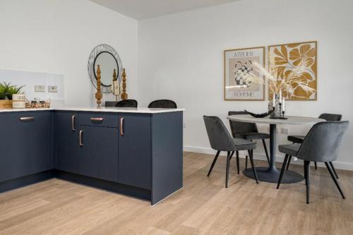 a dining room with a table and a blue cabinet at Luxury 2 Bedroom with Gym, Workspace, Balcony, Free Parking and 3 mins walk to train station in Walton-on-Thames