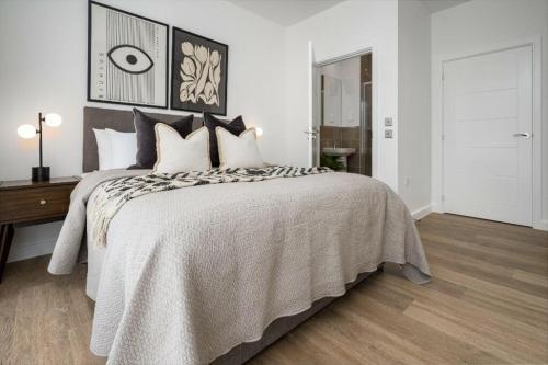 a white bedroom with a large bed with pillows at Luxury 2 Bedroom with Gym, Workspace, Balcony, Free Parking and 3 mins walk to train station in Walton-on-Thames