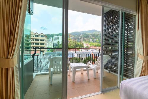 a bedroom with a balcony with a table and chairs at Andakira Hotel - SHA Extra Plus in Patong Beach