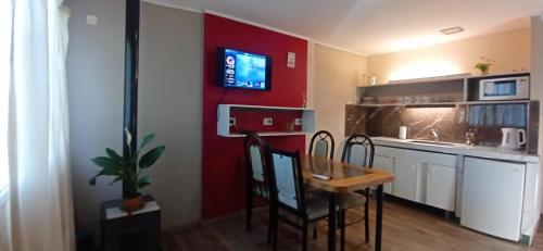 a kitchen with a table and a red wall at Cabañas Nubes del Plata in Potrerillos