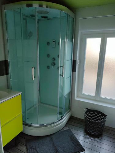 La salle de bains est pourvue d'une douche en verre et d'une fenêtre. dans l'établissement Le sensoriel, à Danvou