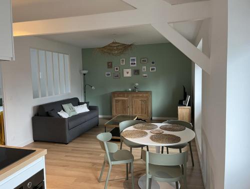 un salon avec une table, des chaises et un canapé dans l'établissement Appartement Le POULIGUEN, au Pouliguen