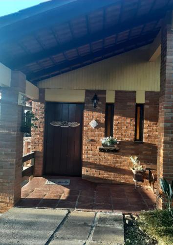 a brick house with a large wooden door at Casa Bela Serra, 5 quartos, excelente localização in Bento Gonçalves
