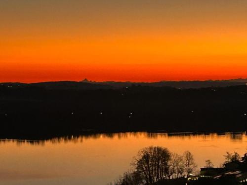 a sunset over a body of water with trees at Terrazza Mirabella in Gavirate