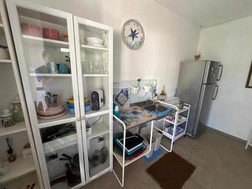a kitchen with a refrigerator and a table and a clock at Delizioso appartamento a ridosso del mare del Plemmirio Siracusa in Plemmirio