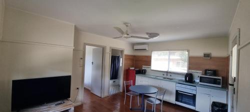 a kitchen with a television and a table and chairs at Park Beach Holiday Cabins in Coffs Harbour