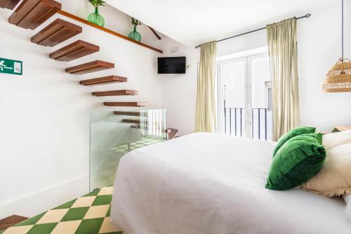 a bedroom with a white bed and a staircase at Casa Callejita del Clavel in Zafra