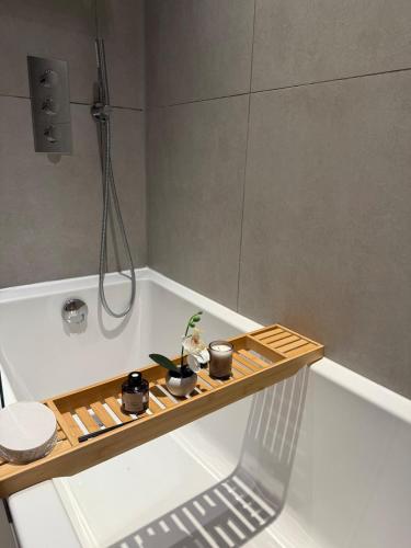 a bath tub with a wooden trayasteryasteryasteryasteryasteryasteryasteryasteryastery at Cozy Luxury Apartment In The Heart Of Slough -The Bethel Suite in Slough