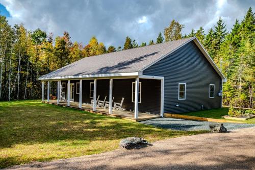 a large blue house with a large porch at Newly Built Retreat in the Woods Near Acadia in Trenton