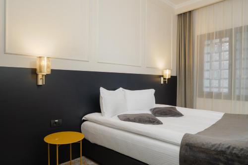 a hotel room with a bed and a yellow stool at Hotel Atria in Braşov