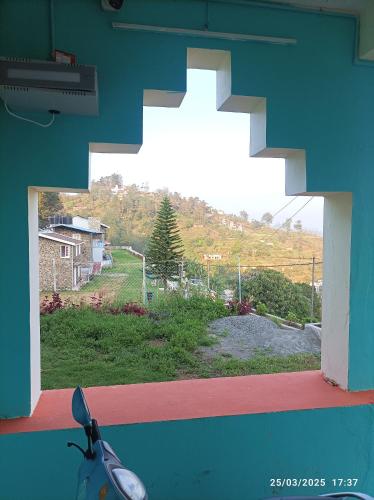 a window with a view of a hill from a house at Akshay INN in Kodaikānāl