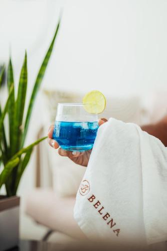 a person holding a blue drink with a lime in a glass at Belena Maldives in Thoddoo