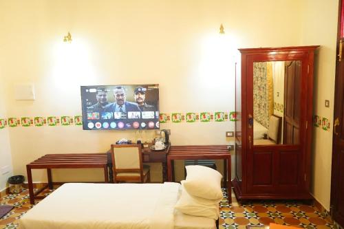 a bedroom with a bed and a desk and a table at Deshadan Chola , Thanjavur in Thanjāvūr