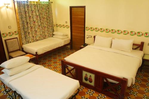 a small room with two beds and a chair at Deshadan Chola , Thanjavur in Thanjāvūr