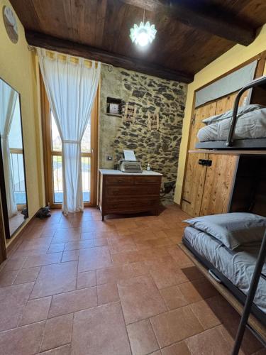 a bedroom with a bed and a desk and a window at Casa Le Scese Porta di Valtellina in Piantedo
