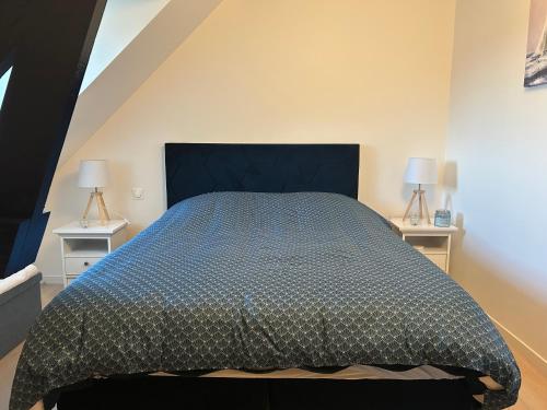 a bedroom with a bed with a blue comforter at Havre de paix in Vimoutiers
