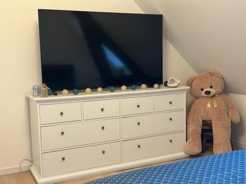 a teddy bear sitting on a dresser with a television on it at Havre de paix in Vimoutiers