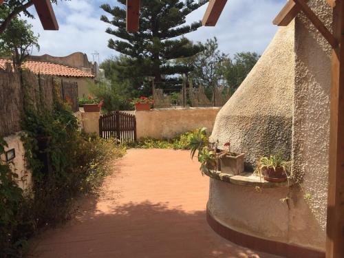 a courtyard with potted plants on a stone wall at Beautiful sea front beach in Granitola