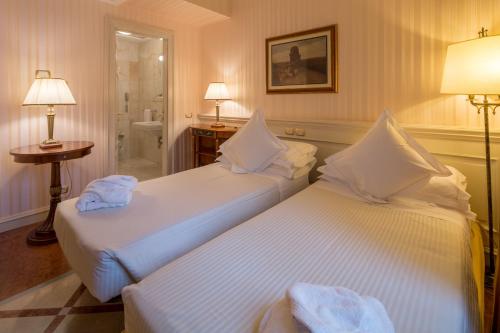 two beds in a hotel room with towels on them at Mercure Petriolo Siena Terme Spa Hotel in Bagni di Petriolo