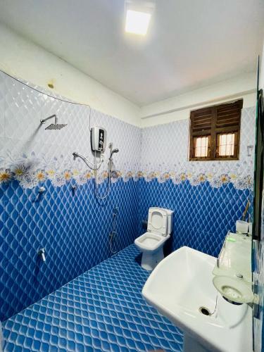 a blue tiled bathroom with a toilet and a sink at Devil mountain guest in Kalupahana