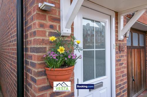 a flower pot on a brick wall next to a door at Three Bedroom Apartment By Vesta Serviced Accommodation & Short Lets Hatfield With Free Parking in Hatfield