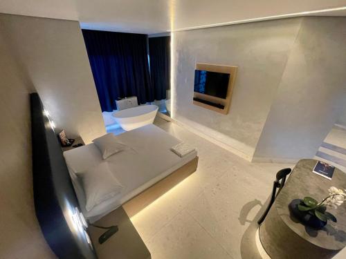a white room with a bed and a television at Le Piège Motel Thematiquè in Almirante Tamandaré