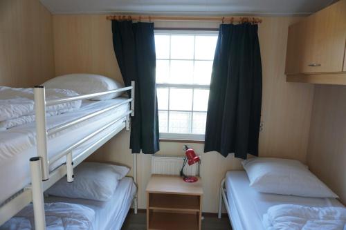 a bedroom with two bunk beds and a window at Kustverhuur, Groede Paarlhof 45 in Groede