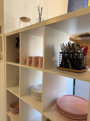 une étagère avec des assiettes et des ustensiles dans l'établissement Rose Arlésien, à Arles