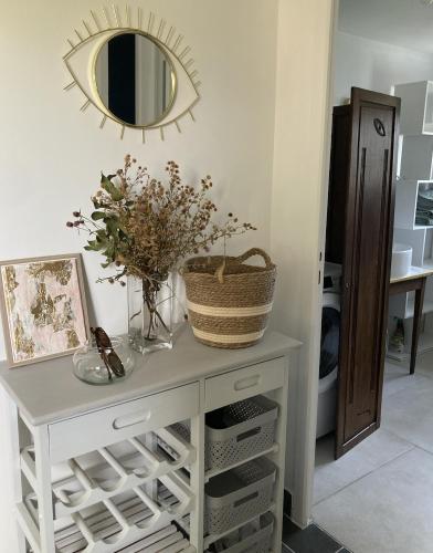 - une commode blanche avec un miroir et des fleurs dans l'établissement Cottage normand de 1930, à Manneville-sur-Risle