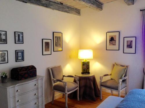 a bedroom with two chairs and a lamp and a dresser at Manoir de Rieuzal in Loubressac