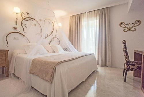 a white bedroom with a bed and a chair at Hotel Sa Volta in Es Pujols