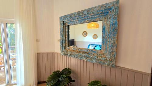 a mirror with a blue frame on a wall at LAKAZ DEL SOL - Modern and elegant apartments with luxurious garden, pool and barbecue area - Tourism Permit Certified in Tamarin