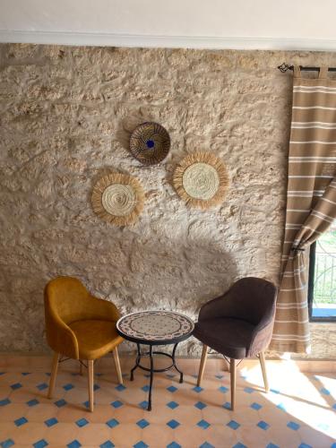 two chairs and a table in front of a wall at Villa AMMA in Essaouira