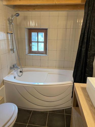 La salle de bains est pourvue d'une baignoire blanche et d'une fenêtre. dans l'établissement Maison Typique Lotoise Saint Cirq Lapopie, à Saint-Cirq-Lapopie