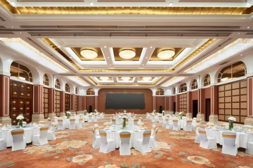 a large banquet hall with tables and a screen at Crowne Plaza Zhenjiang by IHG in Zhenjiang
