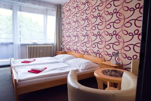 a small bedroom with a bed and a chair at Hotel Zimní stadion Náchod in Náchod