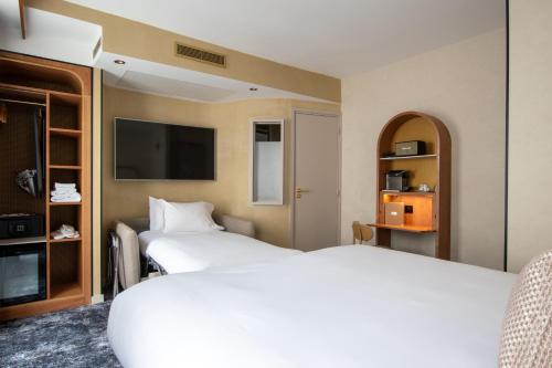 a hotel room with two beds and a flat screen tv at Hotel Du Cadran in Paris