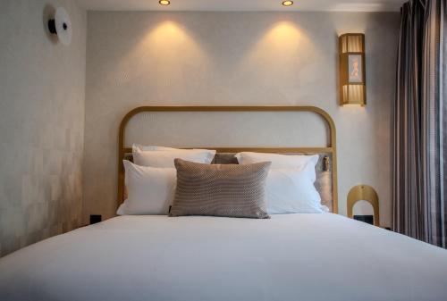 a bed with white sheets and pillows in a room at Hotel Du Cadran in Paris