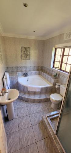 a bathroom with a tub and a toilet and a sink at Gorgeous Garden Villa 3 in Gillitts