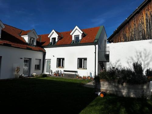 a white house with a red roof and a yard at FERIEN DOMIZIL Neusiedlersee in Breitenbrunn
