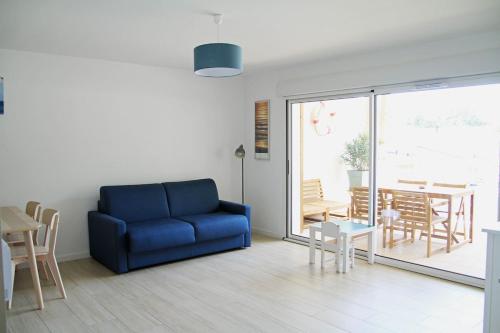 un salon avec un canapé bleu et une table dans l'établissement Appartement neuf T2 50m2 calme et spacieux près de la plage et golf avec grand balcon privé, à Seignosse