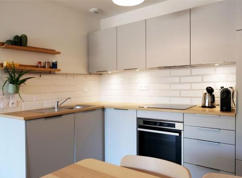 une cuisine avec des armoires blanches et un évier dans l'établissement Appartement neuf T2 50m2 calme et spacieux près de la plage et golf avec grand balcon privé, à Seignosse