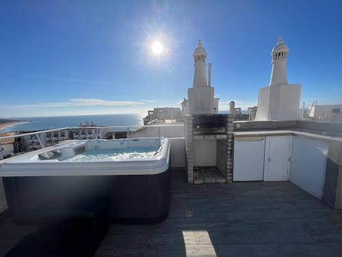 a bath tub sitting on top of a balcony with the ocean at Casa rooftop jacuzzi and magnificent sea view in Albufeira