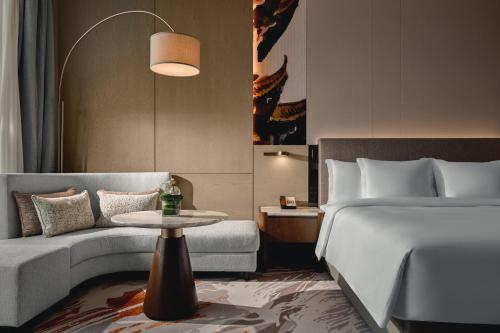 a bedroom with a bed and a couch and a table at Crowne Plaza Wuhan Tianhe Airport by IHG in Wuhan