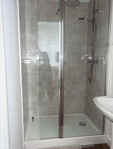une douche avec une porte vitrée à côté d'un lavabo dans l'établissement L'Aparté à 5min de la plage de Hardelot, à Neufchâtel-Hardelot