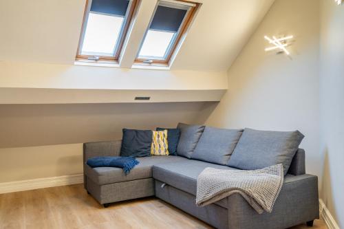 a grey couch in a room with windows at The Shambles - Attic in York