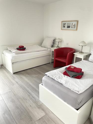 ein Schlafzimmer mit zwei Betten und einem roten Stuhl in der Unterkunft Privatquartier 73 in Wietzen